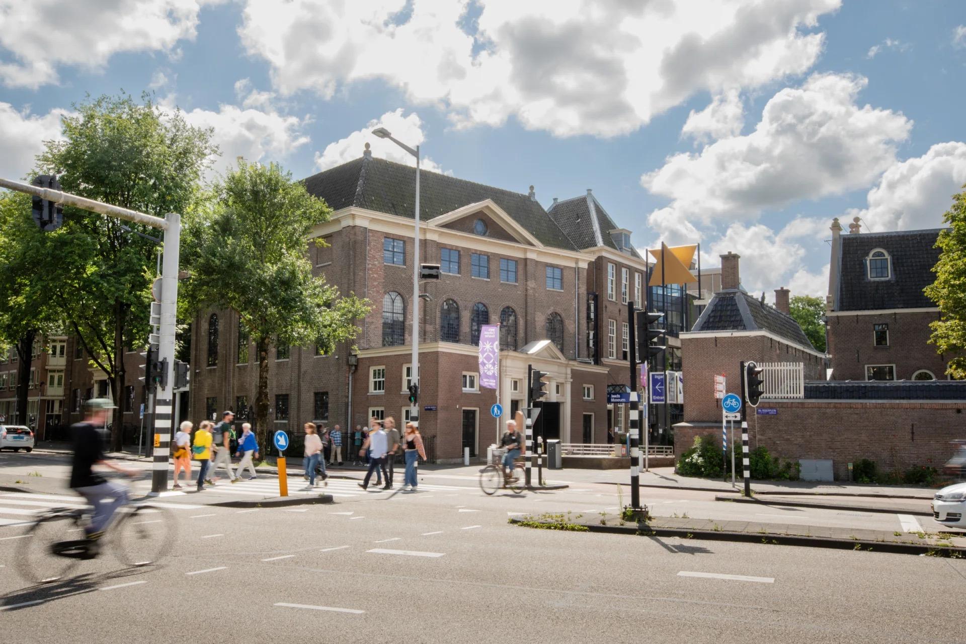 The Jewish Museum in Amsterdam seen from the junction, with pedestrians crossing in front of the eighteenth century brick facade