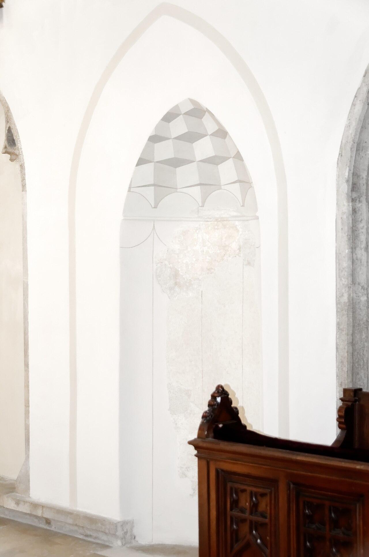 Pointed-arch niche in a white church wall with a scalloped motif in the arch head, the Turkish prayer niche