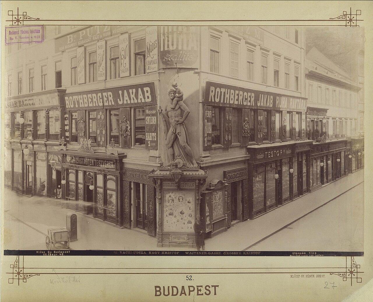 Old photograph of a corner building with a large statue of Saint Christopher above the shopfronts